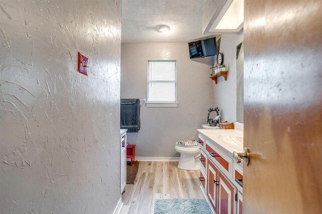 814 Branding Iron Trl, Granbury, TX 76049 - half bathroom featuring wood finished floors, vanity, baseboards, a textured ceiling, and toilet
