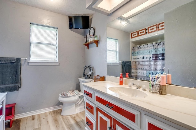814 Branding Iron Trl, Granbury, TX 76049 - full bath with a skylight, wood finished floors, toilet, vanity, and a textured ceiling