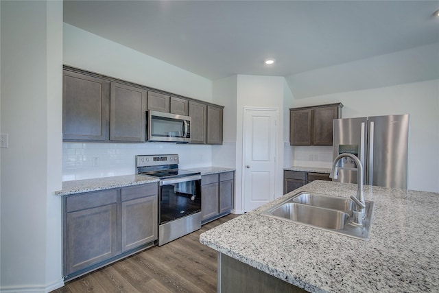 2229 Darner Dr, Fate, TX 75189 - kitchen featuring appliances with stainless steel finishes, a sink, dark wood-style floors, decorative backsplash, and dark brown cabinetry