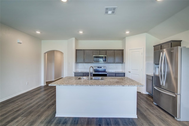 2229 Darner Dr, Fate, TX 75189 - kitchen with stainless steel appliances, arched walkways, a sink, a kitchen island with sink, and backsplash
