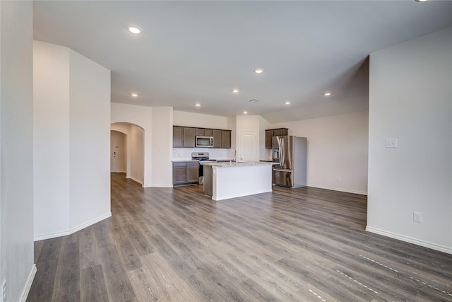2229 Darner Dr, Fate, TX 75189 - unfurnished living room featuring arched walkways, dark wood-style flooring, baseboards, and recessed lighting