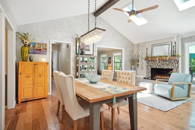 1010 Kings Canyon Ct, Grapevine, TX 76051 - dining room featuring light wood-style floors, ceiling fan, high vaulted ceiling, a skylight, and a fireplace