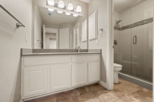 904 Blue Jay Ln, Coppell, TX 75019 - full bathroom with toilet, a shower stall, vanity, a textured wall, and tile patterned floors