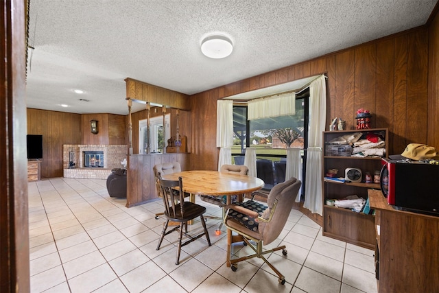 150 N Powell Dr, Hubbard, TX 76648 - tiled dining room featuring a fireplace, wooden walls, and a textured ceiling