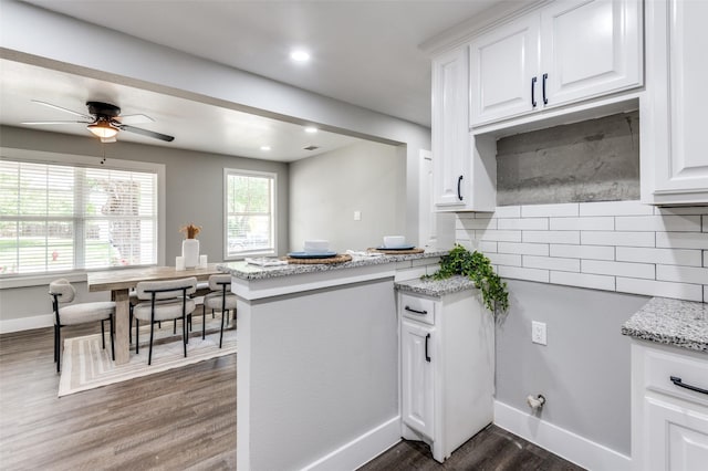 437 22nd St, Grand Prairie, TX 75050 - kitchen featuring dark wood-type flooring, backsplash, white cabinets, light stone countertops, and a ceiling fan