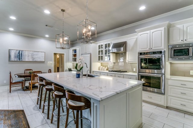 971 Condor Dr, Coppell, TX 75019 - kitchen with built in appliances, a center island with sink, a kitchen bar, tasteful backsplash, and ornamental molding