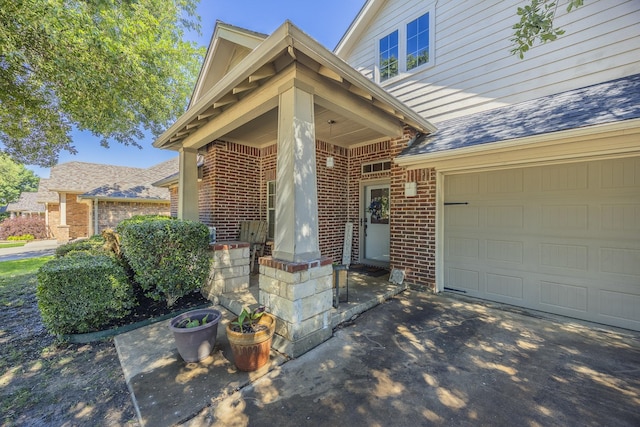 view of exterior entry with brick siding, a garage, driveway, and a shingled roof