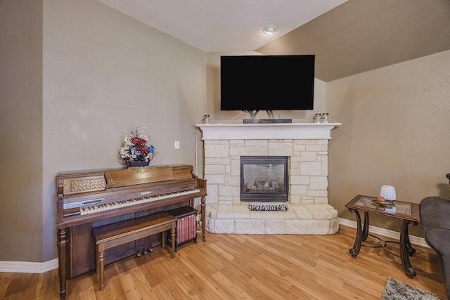 living room with wood finished floors, lofted ceiling, baseboards, and a fireplace