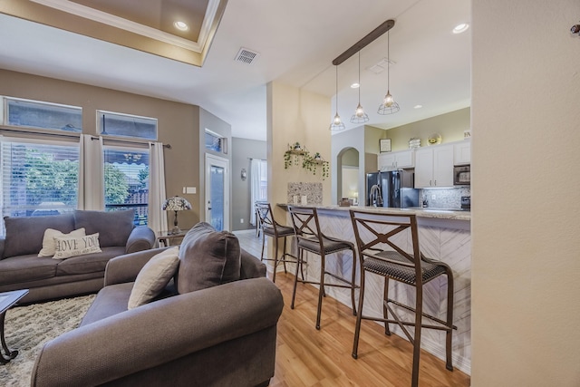 living area featuring ornamental molding, light wood-type flooring, and recessed lighting