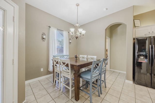 dining room featuring arched walkways, light tile patterned floors, a chandelier, and baseboards