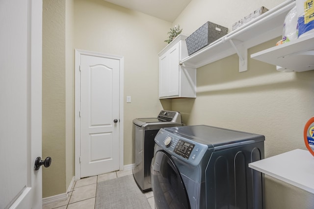laundry room featuring cabinet space, washing machine and dryer, light tile patterned floors, and baseboards