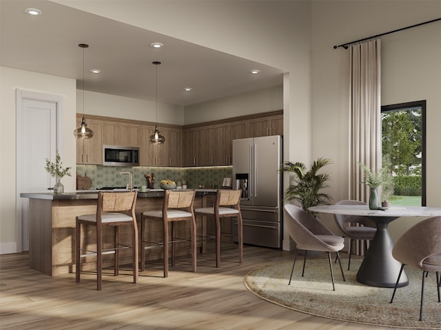 kitchen featuring stainless steel appliances, light wood-type flooring, a kitchen breakfast bar, backsplash, and recessed lighting