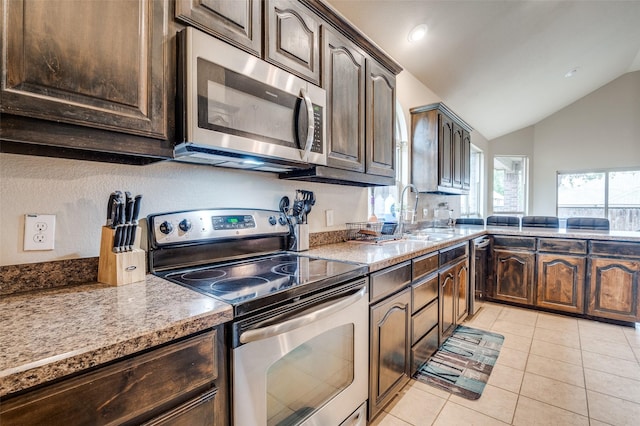 kitchen with appliances with stainless steel finishes, a sink, dark brown cabinets, lofted ceiling, and light tile patterned floors