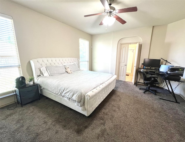 carpeted bedroom with an office area and a ceiling fan