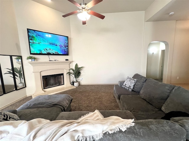 carpeted living room with a ceiling fan, arched walkways, and a glass covered fireplace