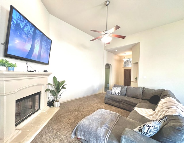carpeted living room with arched walkways, a ceiling fan, and a glass covered fireplace