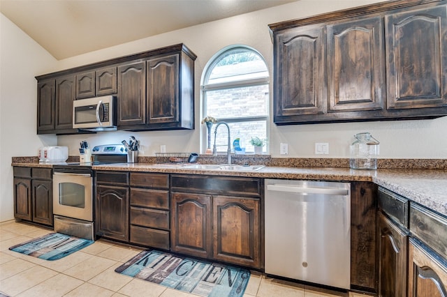 kitchen featuring stainless steel appliances, a sink, dark brown cabinetry, light tile patterned floors, and lofted ceiling