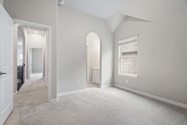 720 Waterbrook Pkwy, Argyle, TX 76226 - unfurnished bedroom featuring arched walkways, light colored carpet, baseboards, vaulted ceiling, and ensuite bath
