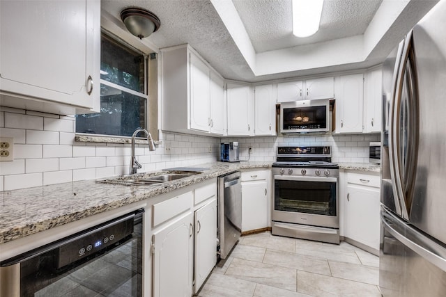 2708 Winchester Ct, Denton, TX 76209 - kitchen with stainless steel appliances, a sink, beverage cooler, a textured ceiling, and white cabinetry