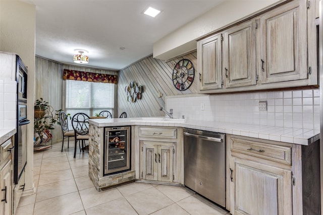 kitchen with black appliances, wine cooler, a peninsula, a sink, and light tile patterned floors
