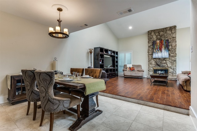 dining room with a chandelier, light tile patterned floors, high vaulted ceiling, and a fireplace