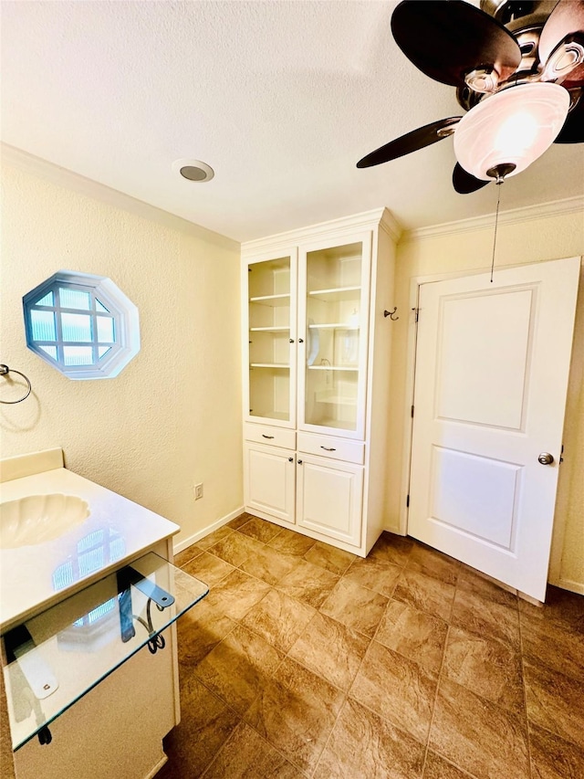 408 Briarwood Dr, Eastland, TX 76448 - bathroom featuring ceiling fan, a textured ceiling, ornamental molding, baseboards, and vanity