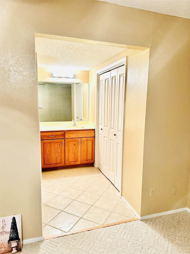 408 Briarwood Dr, Eastland, TX 76448 - corridor with a sink, baseboards, light colored carpet, and a textured ceiling