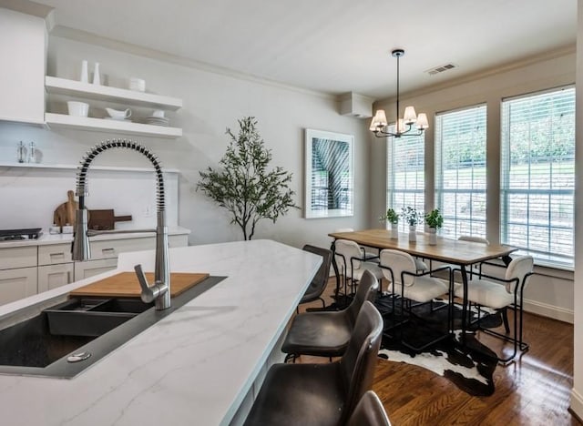 dining area with dark wood-style flooring, plenty of natural light, a chandelier, and crown molding