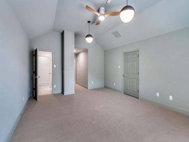 empty room with vaulted ceiling, light colored carpet, a ceiling fan, and baseboards