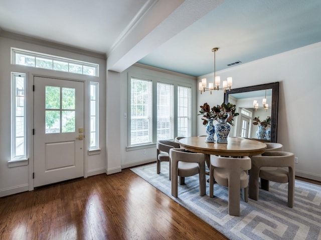 dining area featuring a chandelier, ornamental molding, baseboards, and wood finished floors