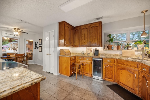 2608 Rivercrest Dr, Arlington, TX 76006 - kitchen with beverage cooler, backsplash, a textured ceiling, a sink, and brown cabinets
