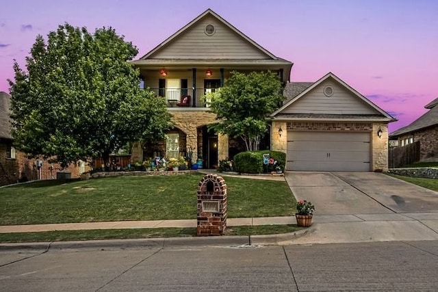 view of front of home featuring driveway, a front yard, a balcony, stone siding, and a garage