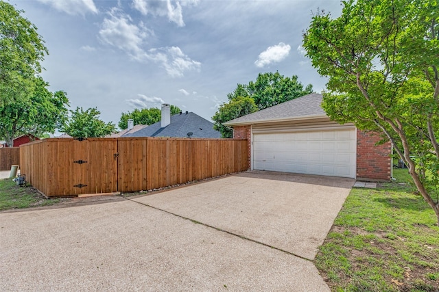 view of side of property with brick siding, fence, concrete driveway, and a shingled roof