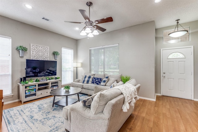 living room featuring a ceiling fan, light wood-type flooring, baseboards, a textured ceiling, and recessed lighting