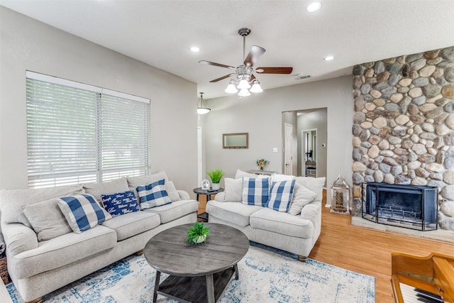 living area featuring a ceiling fan, wood finished floors, recessed lighting, and a stone fireplace