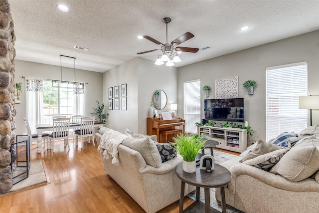 living area with a textured ceiling, light wood-style floors, a ceiling fan, and recessed lighting