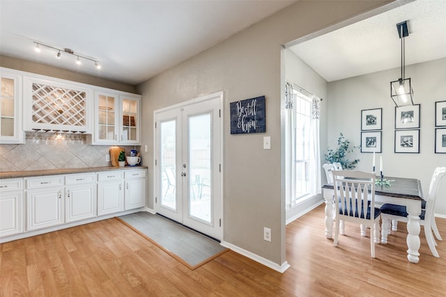 kitchen featuring french doors, light wood-style flooring, tasteful backsplash, and white cabinets