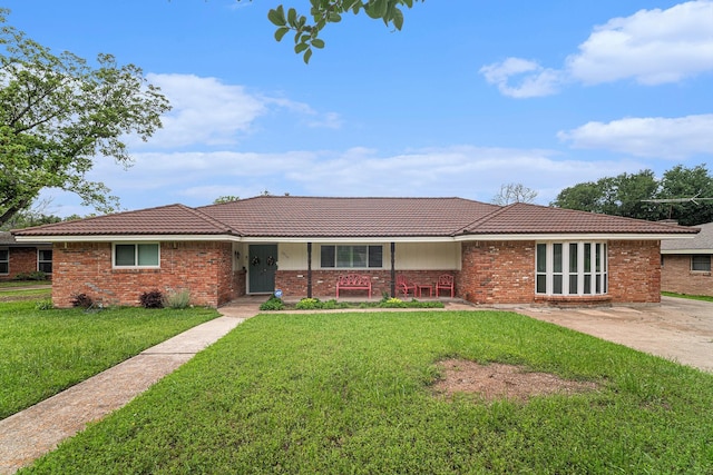 ranch-style home with a tiled roof, a front lawn, brick siding, and a porch
