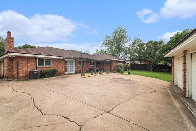 back of house with french doors, central air condition unit, a tiled roof, brick siding, and a patio area