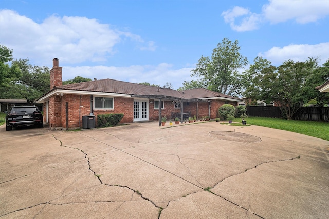 back of property with french doors, a tiled roof, fence, brick siding, and a chimney