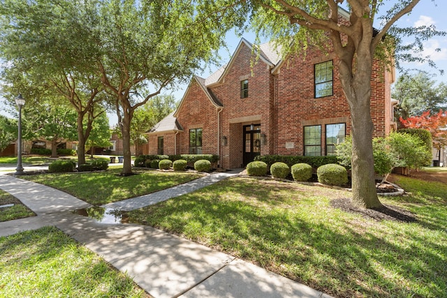 traditional home with brick siding, a front lawn, and french doors