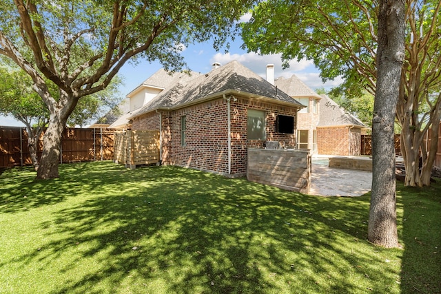 rear view of house with area for grilling, brick siding, roof with shingles, and a patio area