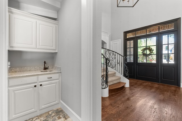 entryway with stairs, dark wood-style floors, and wet bar