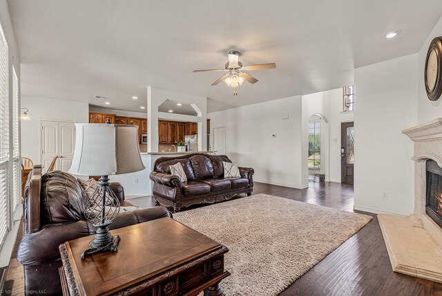 1837 Trail Dr, Rockwall, TX 75087 - living room featuring a glass covered fireplace, ceiling fan, dark wood-type flooring, arched walkways, and baseboards