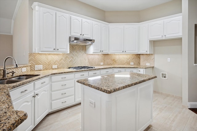 11968 Cobblestone Dr, Frisco, TX 75035 - kitchen with under cabinet range hood, a sink, stainless steel gas cooktop, light stone counters, and tasteful backsplash