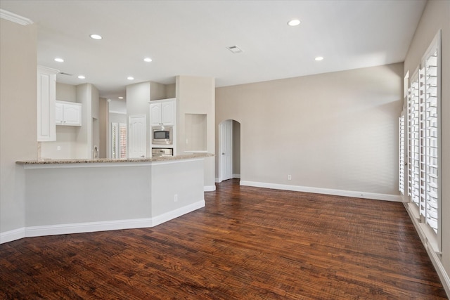 11968 Cobblestone Dr, Frisco, TX 75035 - unfurnished living room featuring arched walkways, dark wood-style floors, baseboards, and recessed lighting