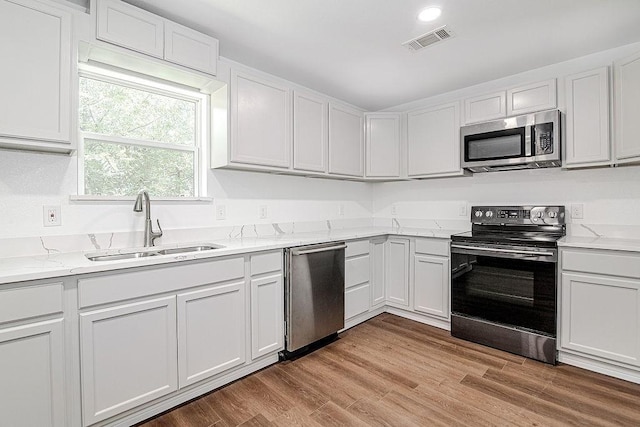 1021 Pangburn St, Grand Prairie, TX 75051 - kitchen with stainless steel appliances, a sink, light stone counters, white cabinetry, and recessed lighting
