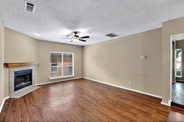 1523 Allen Dr, Cedar Hill, TX 75104 - unfurnished living room with a ceiling fan, wood finished floors, a tiled fireplace, baseboards, and a textured ceiling