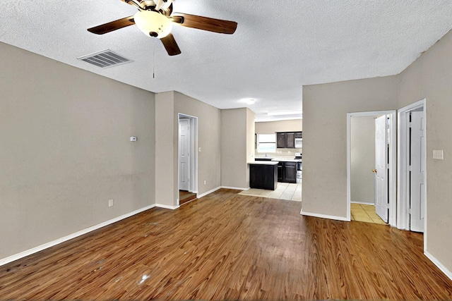 1523 Allen Dr, Cedar Hill, TX 75104 - unfurnished living room with light wood-style floors, a ceiling fan, a textured ceiling, and baseboards
