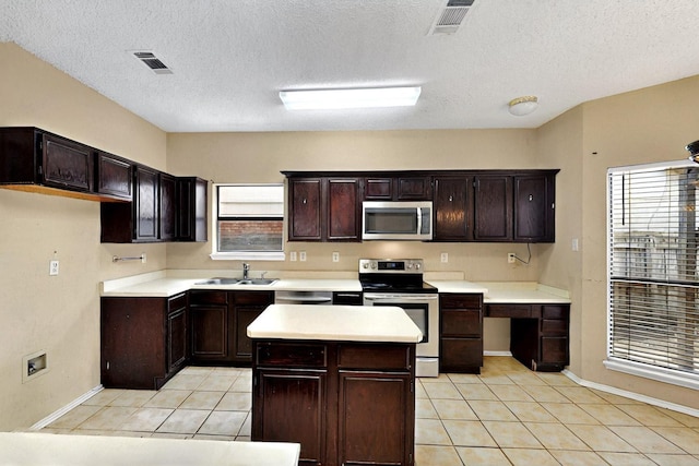1523 Allen Dr, Cedar Hill, TX 75104 - kitchen with stainless steel appliances, a sink, light tile patterned flooring, healthy amount of natural light, and a textured ceiling